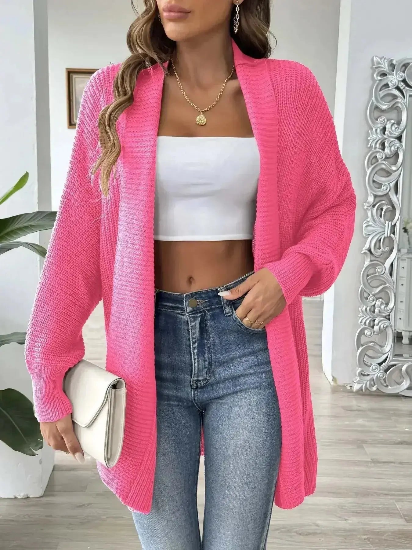 Bright pink knit cardigan over white crop top with high-waisted jeans, stylish women's fashion outfit