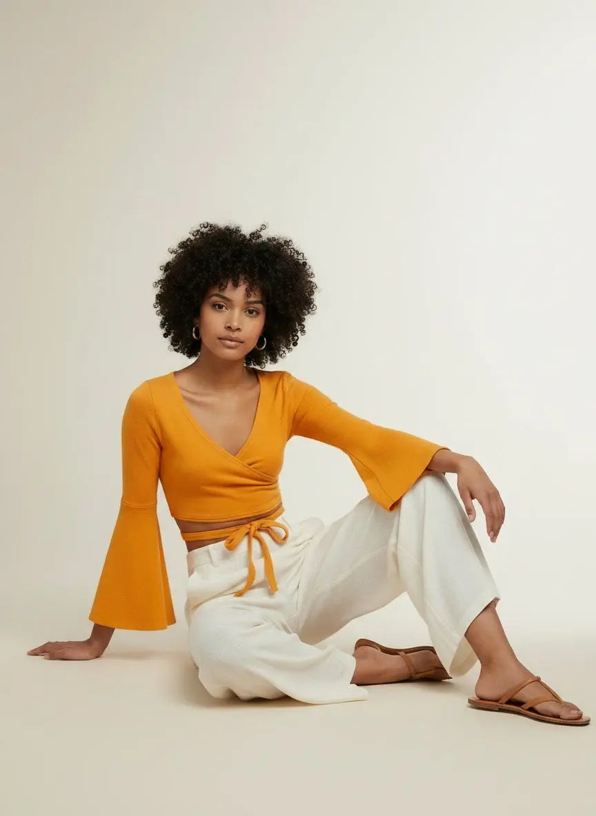 Model sitting while wearing Tie Front Flare Sleeve Cropped Top