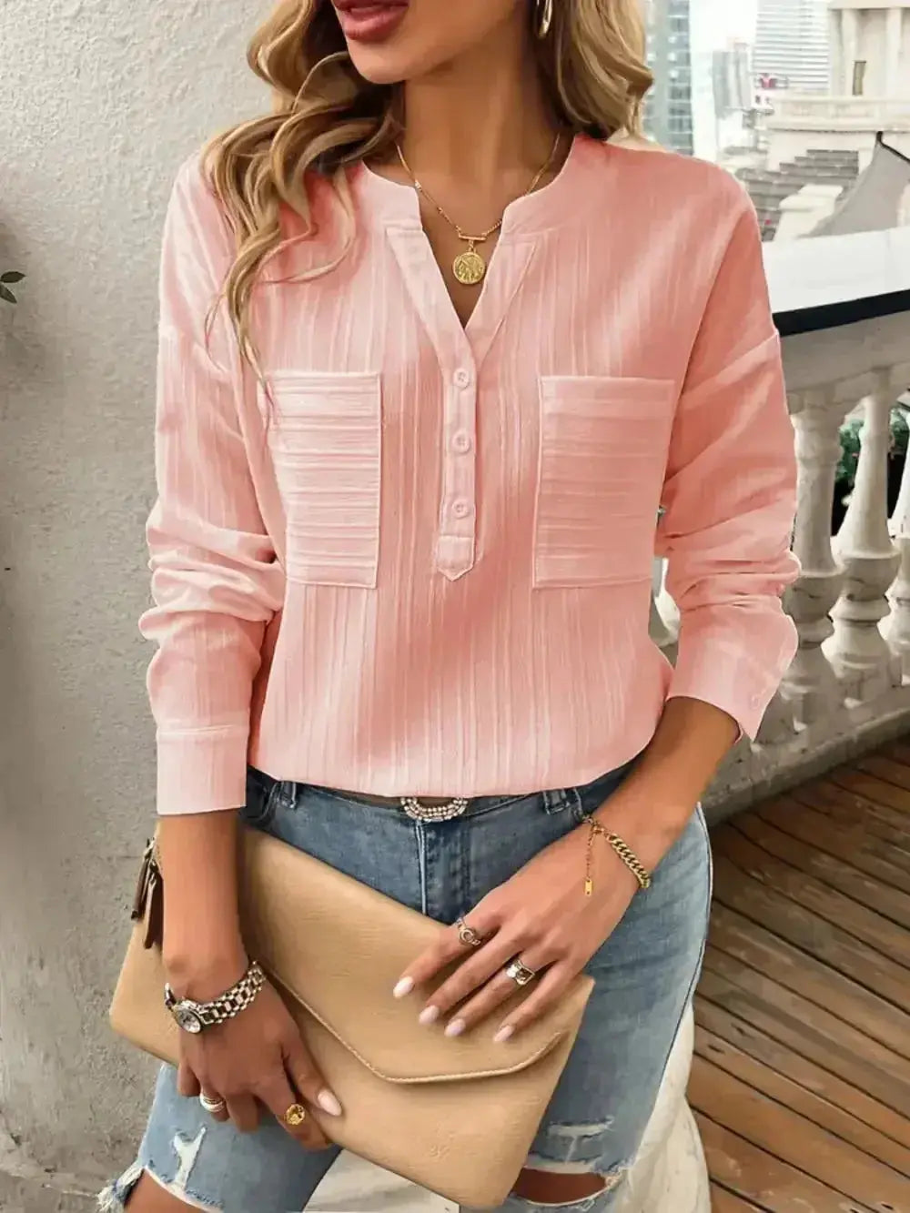 Pink long sleeve blouse with front pockets, paired with ripped jeans and a beige clutch, modern women's fashion