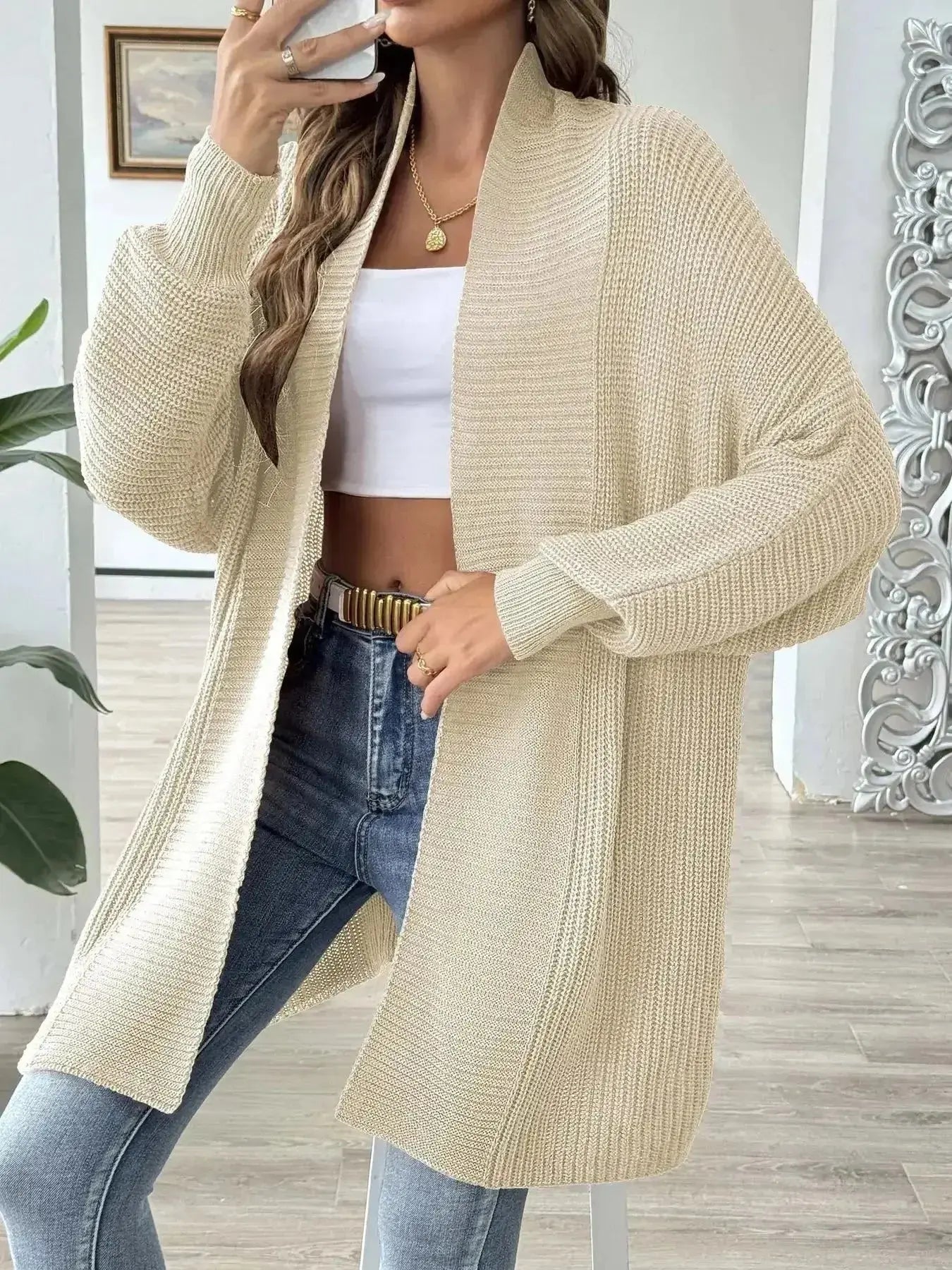 Beige knit cardigan with white crop top and blue jeans, modern minimalist women's fashion
