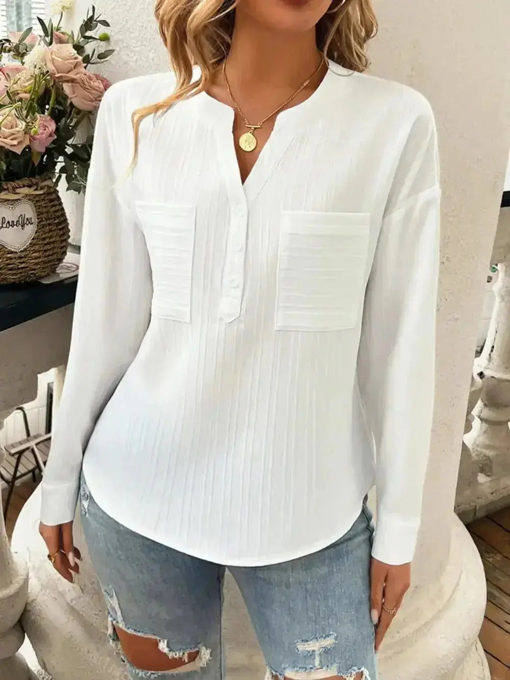 White long-sleeve blouse with front pockets, paired with ripped jeans for casual chic style