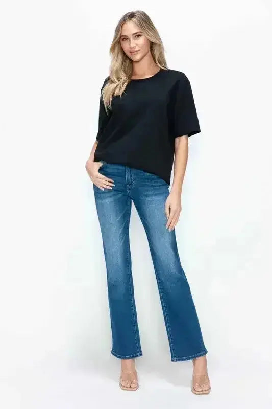 Woman in black short sleeve top and blue flared jeans, modern minimalist women's fashion