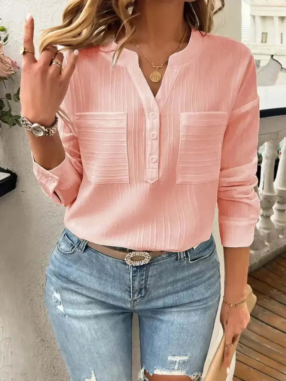 Pink long-sleeve button-up blouse with pockets, paired with ripped jeans and gold accessories