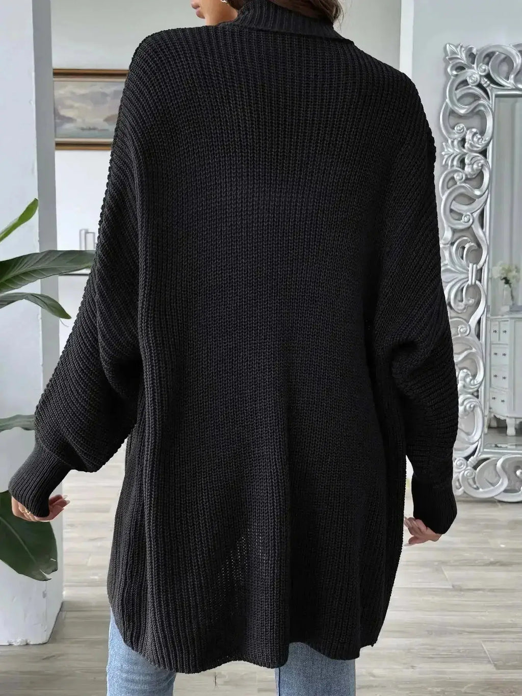 Black oversized knit cardigan with ribbed texture, paired with jeans, modern minimalist style