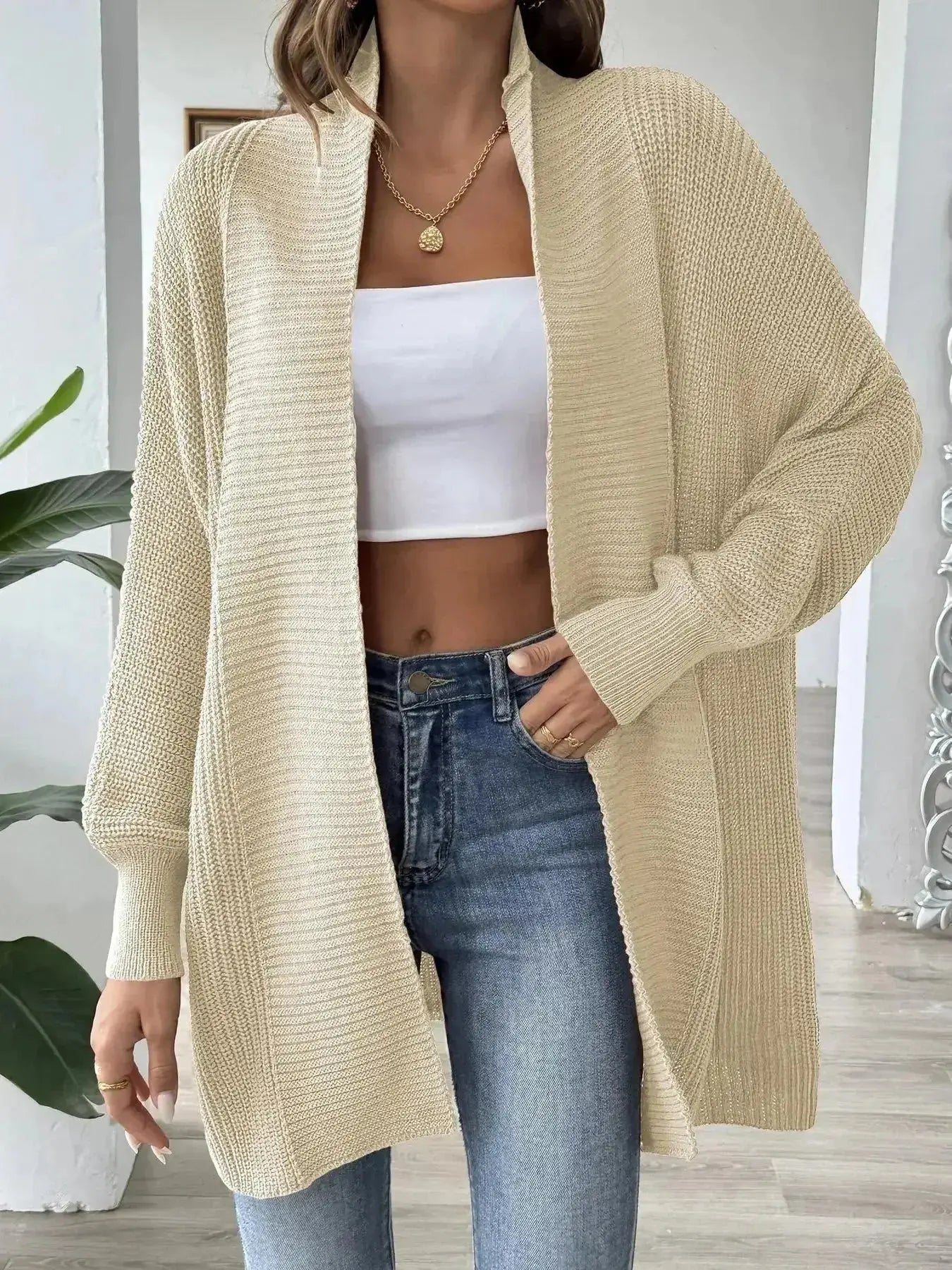 Beige knit cardigan with white crop top and blue jeans, modern minimalist women's fashion