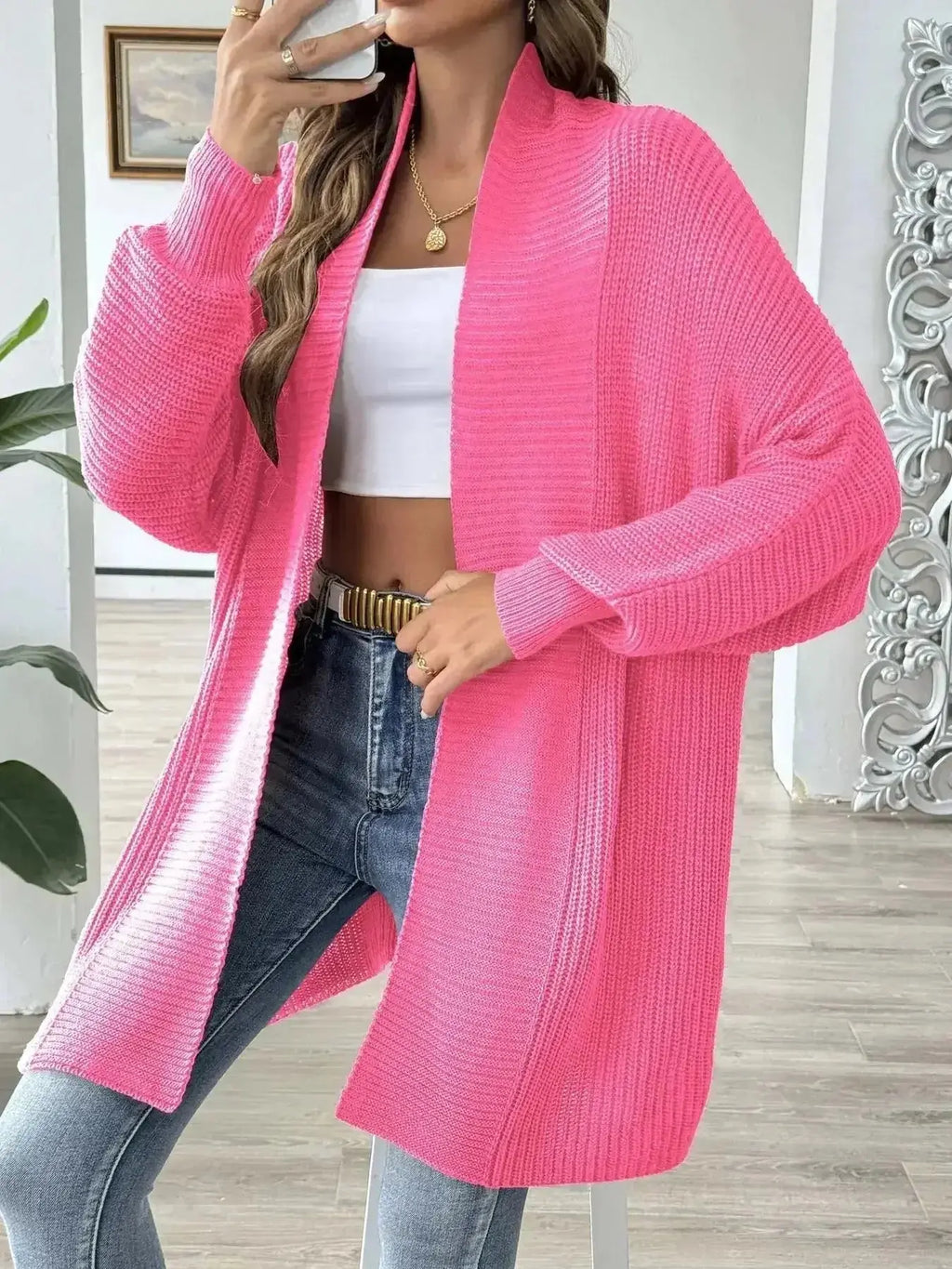 Bright pink ribbed knit cardigan paired with white crop top and jeans for modern minimalist style