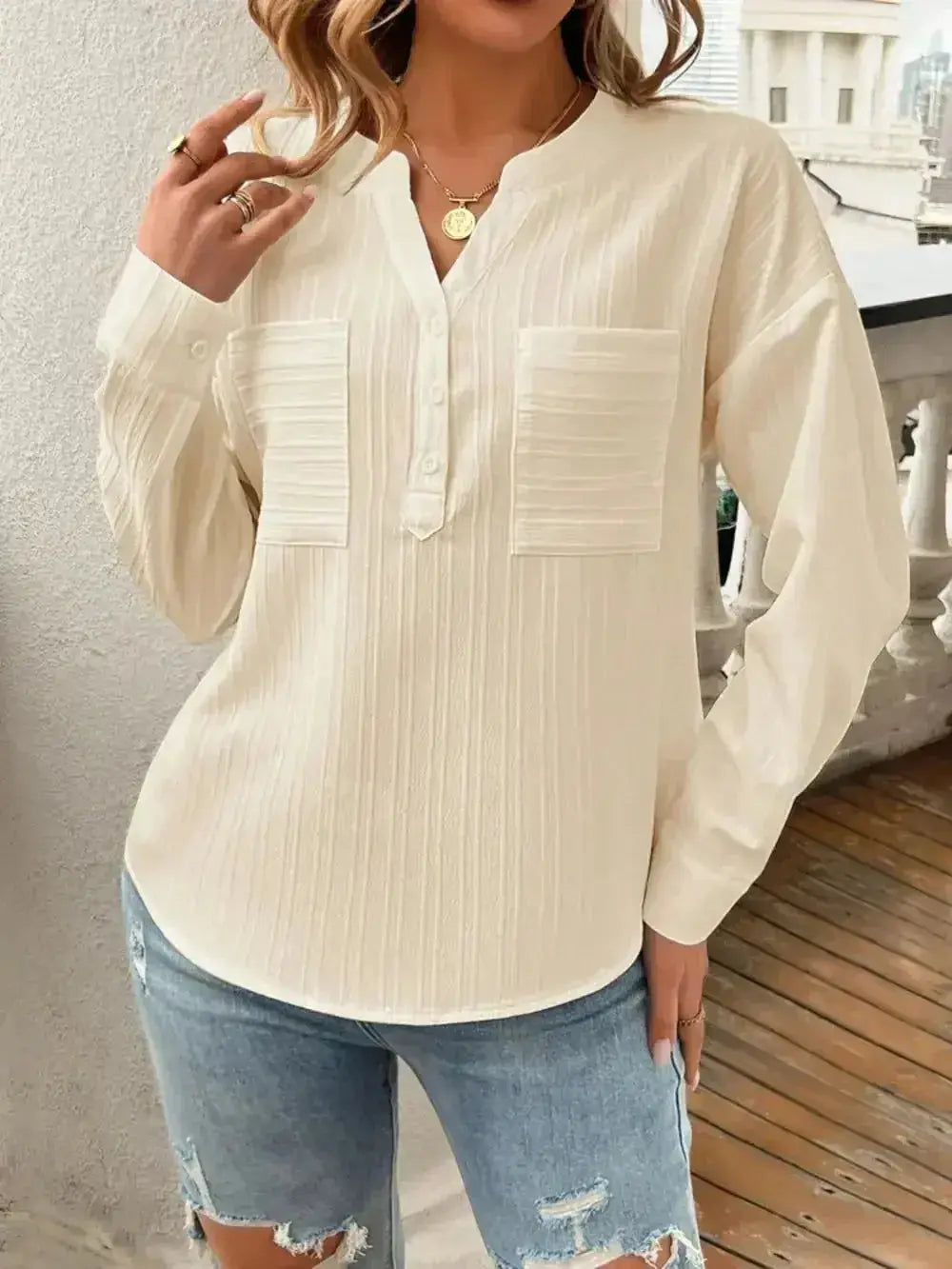 Cream long sleeve button-up blouse with front pockets, paired with distressed denim shorts for casual style